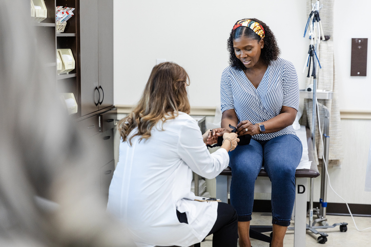 Unrecognizable female ER doctor helps mature woman with orthopedic brace